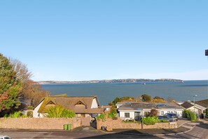 A coastal residential area with houses, a clear view of the sea, and a distant coastline. - Baywatch Sea View Retreat a beautifully refurbished coastal holiday home (Brixham)