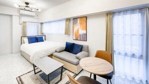 A modern hotel room with a bed, sofa, dining table, and chairs. - Trioni EBISU  (Osaka)