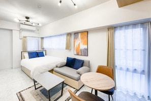 A modern hotel room with a bed, sofa, dining table, and chairs. - Trioni EBISU  (Osaka)
