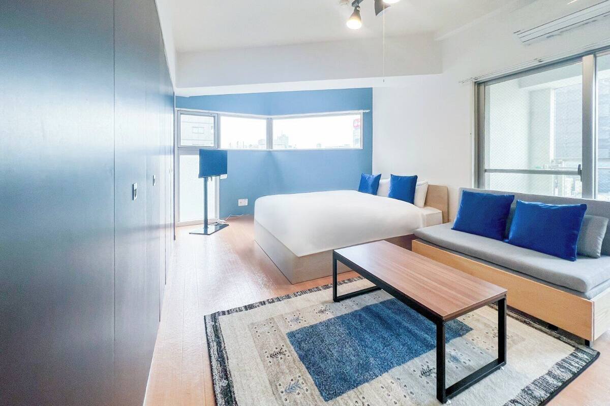 Une chambre moderne avec un grand lit, un canapé, un bureau et une fenêtre donnant sur la ville.
