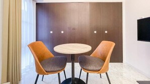A room with a round table, two chairs, a dark wardrobe, and a TV mounted on the wall. - Trioni EBISU  (Osaka)