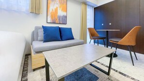 A modern hotel room with a sofa, two chairs, a small table, and a painting on the wall. - Trioni EBISU  (Osaka)