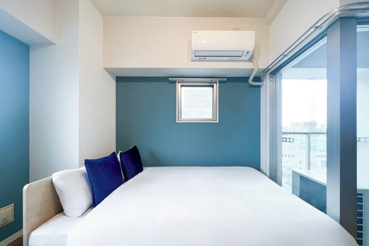 Une chambre d’hôtel avec un lit, une fenêtre et un appareil de climatisation.