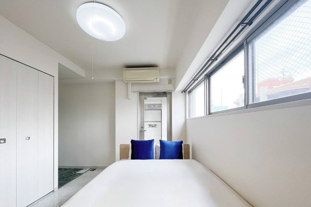 Une chambre d’hôtel moderne équipée d’un lit, d’une armoire, d’un climatiseur et d’une fenêtre.