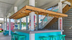 A bar area with wooden beams, teal stools, and a staircase. - Pearly Pelican 3 Bedroom Home (Port Bolivar)