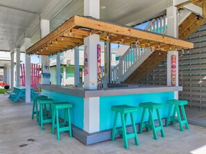 Eine Bar mit Holzbalken, blauen Barhocker und einer Treppe.