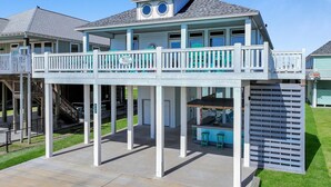 A two-story house with a balcony, a covered patio, and a pool area. - Pearly Pelican 3 Bedroom Home (Port Bolivar)