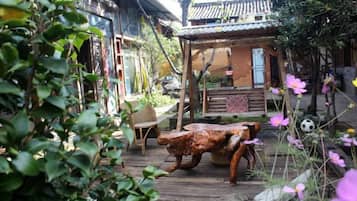 Un edificio de estilo japonés tradicional con una terraza de madera, un sendero de piedra y una zona de estar al aire libre rústica.