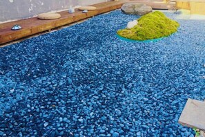 A pebbled area with a wooden border and a green plant. - Leisure Inn Lijiang (Yulong)