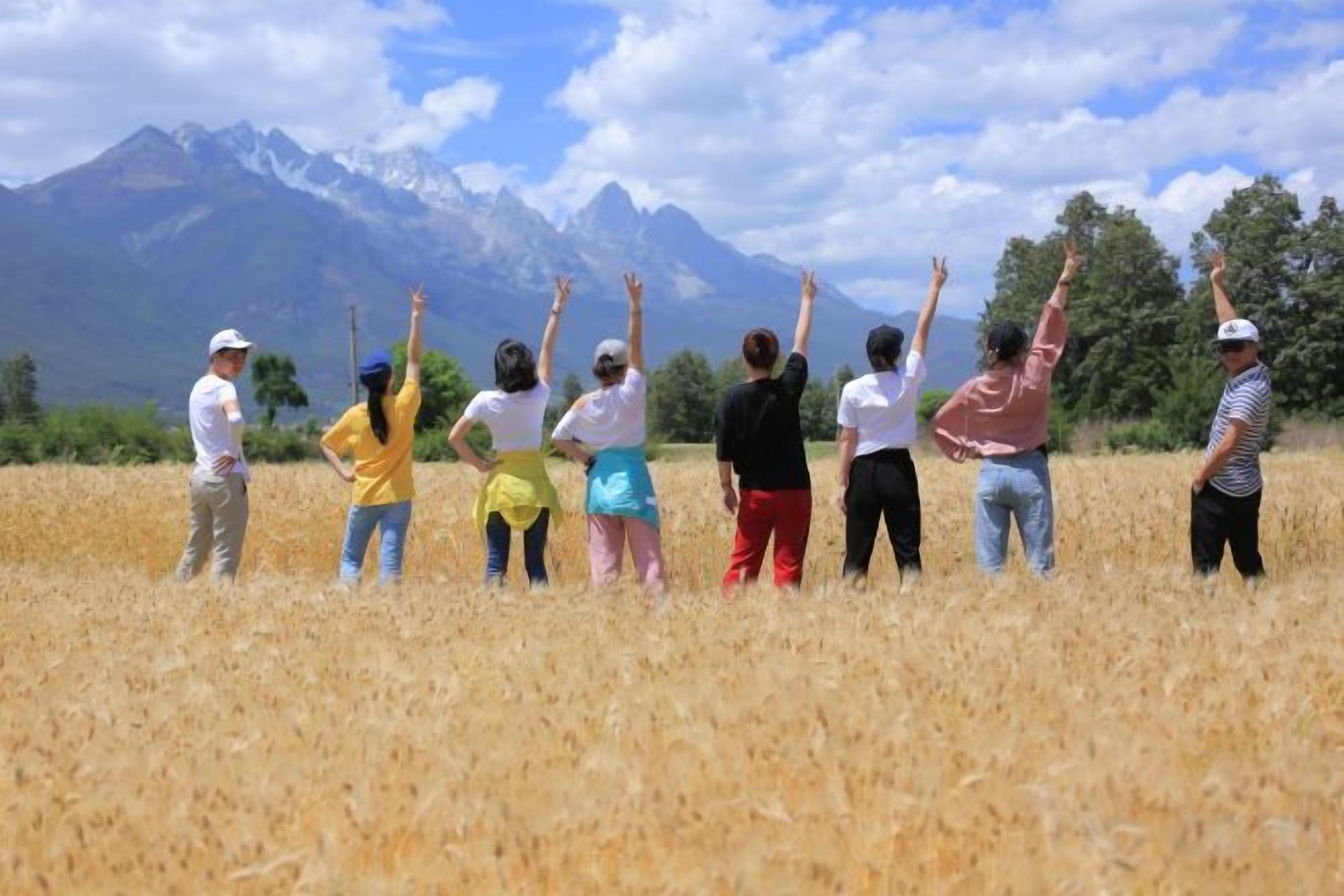 A group of people standing in a field with a mountain in the background.