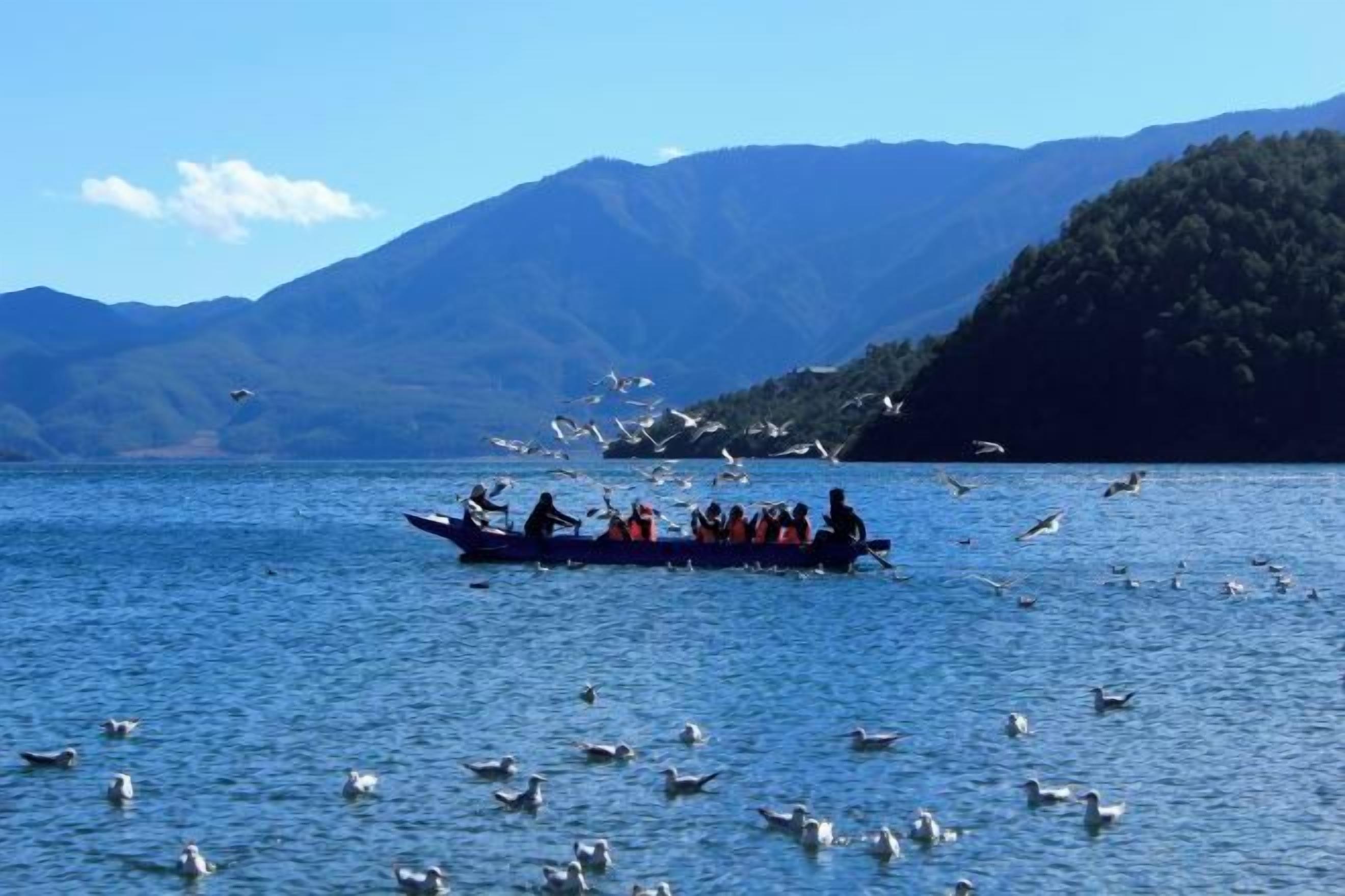 A boat on a lake with mountains in the background.