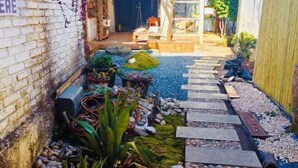 A narrow garden path with stepping stones, surrounded by potted plants and a brick wall. - Leisure Inn Lijiang (Yulong)
