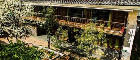 A traditional building with a tiled roof, a balcony with railings, and a garden area with various plants.