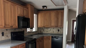 A kitchen with wooden cabinets, a microwave, stove, dishwasher, and a refrigerator.