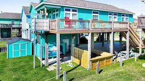 A multi-story house with a wooden deck and a small boat house. - It's A Shellabration 3 Bedroom Home (Port Bolivar)