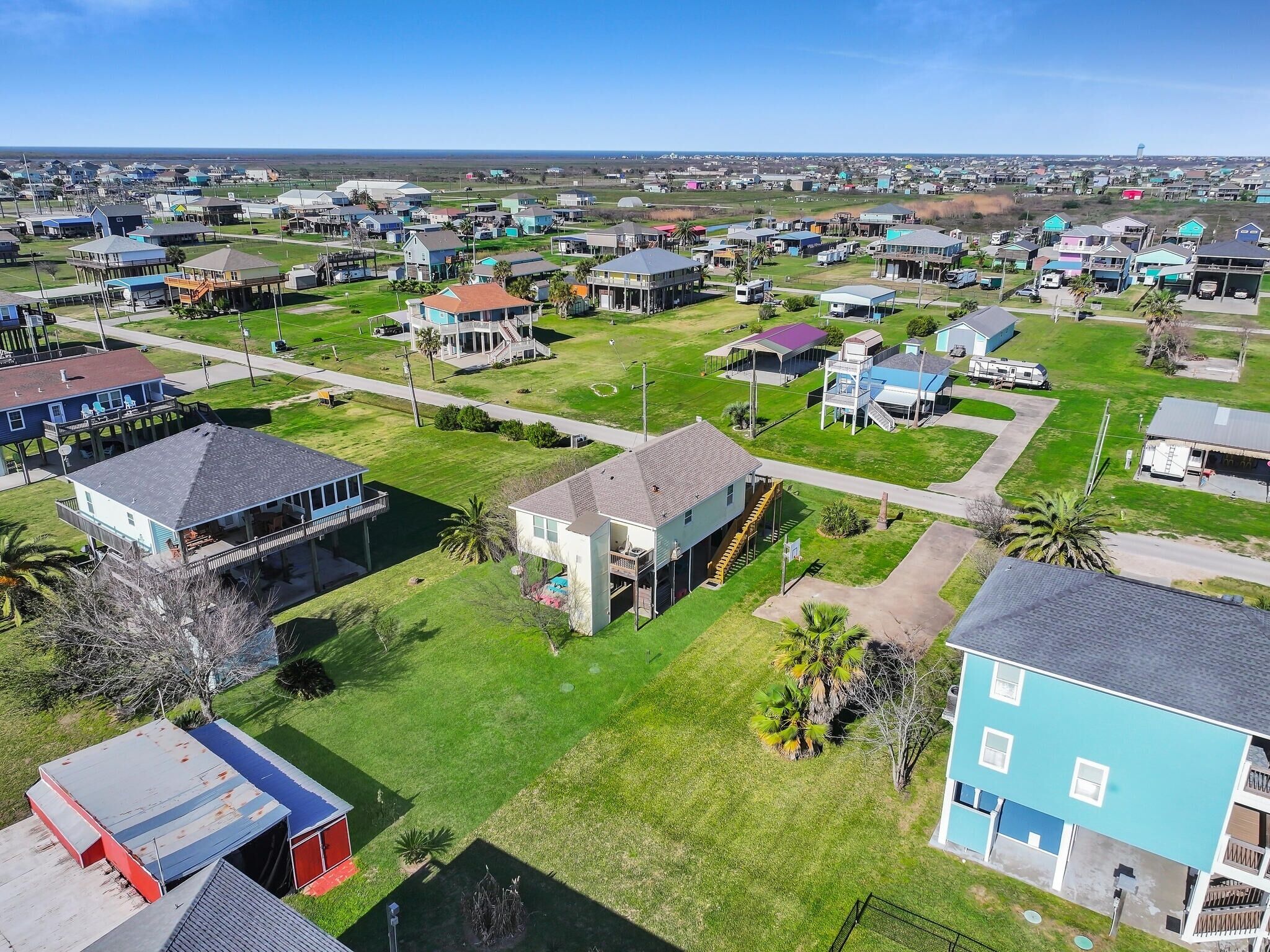 An aerial view of a residential area with houses, a swimming pool, and a water tower in the distance.