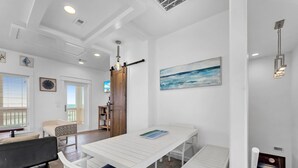 A modern interior with a white dining area, a black sofa, and a view to the outside. - Crystal By The Ocean 4 Bedroom Home (Port Bolivar)
