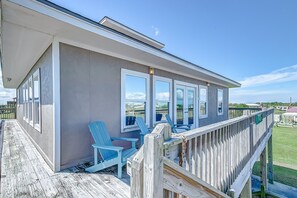 A building with a covered porch, large windows, and a wooden deck. - Amy's Dream 3 Bedroom Home (Port Bolivar)