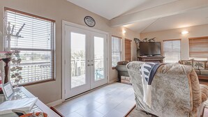 A living room with a sofa, TV, and a door leading to a balcony. - Amy's Dream 3 Bedroom Home (Port Bolivar)