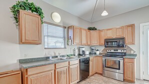 A kitchen with wooden cabinets, a stainless steel dishwasher, a microwave, and an oven. - Amy's Dream 3 Bedroom Home (Port Bolivar)