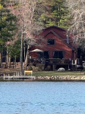 A rustic cabin by a lake with a dock, surrounded by trees. - Charming 3-bedroom lake house on tranquil Wilson Lake near Wild Rose, WI (Wild Rose)