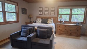 Ein Schlafzimmer mit einem Bett, einem Schminktisch, einem Sessel und einem Nachttisch.