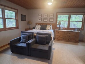 A bedroom with a bed, a dresser, a chair, and a nightstand. - Charming 3-bedroom lake house on tranquil Wilson Lake near Wild Rose, WI (Wild Rose)