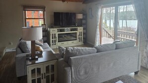 Ein Wohnzimmer mit Sofa, Fernseher, Schrank und Seeblick.