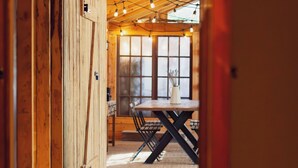 A wooden interior with a dining area, wooden flooring, and string lights.