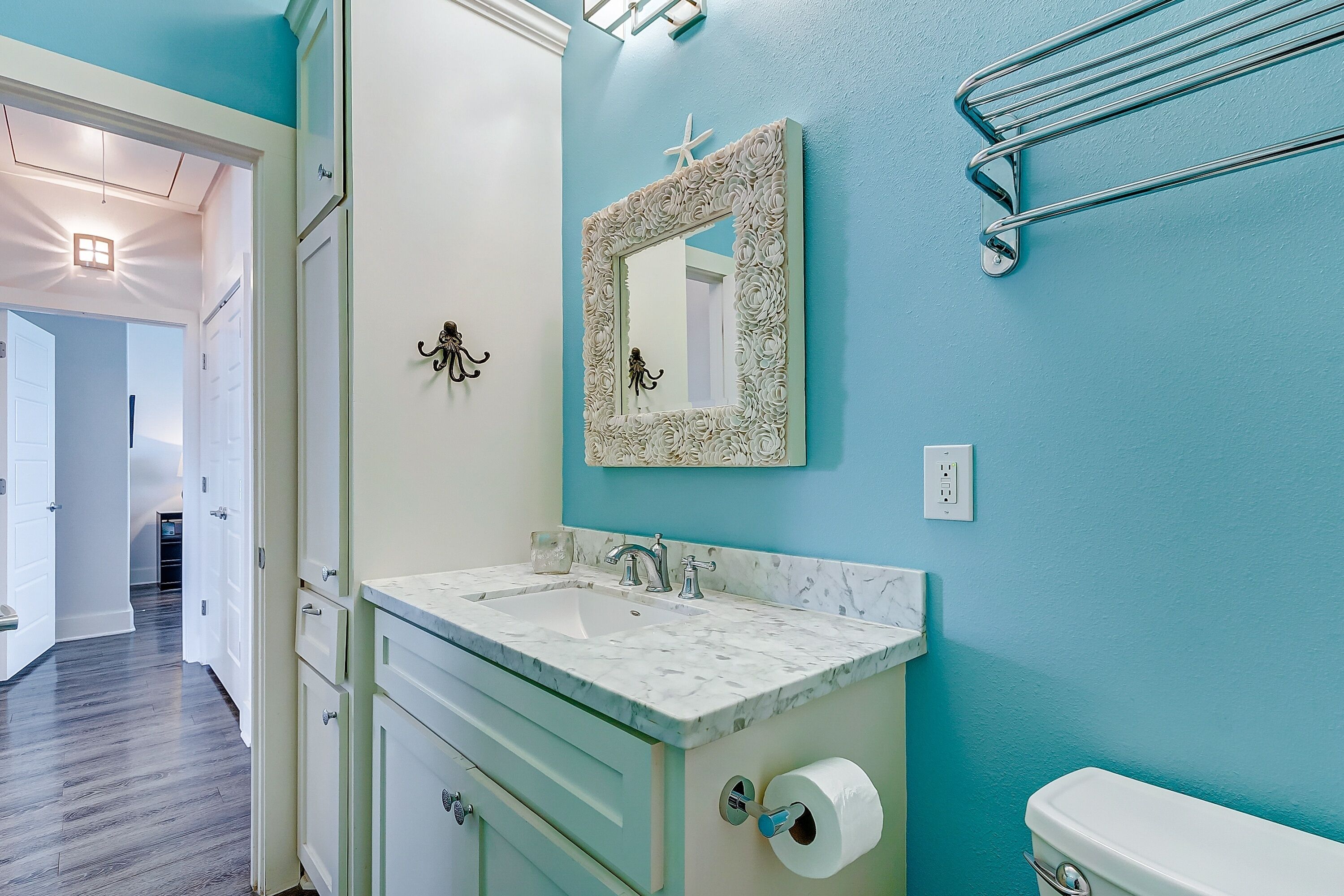 Une salle de bain équipée d’un lavabo, d’un miroir, de toilettes et d’un porte-serviettes.
