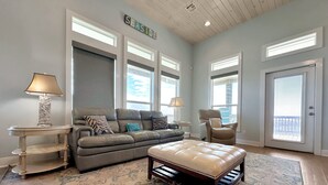 A living room with a sectional sofa, a chaise lounge, a round coffee table, and a patterned rug. - The Salty Mermaid 3 Bedroom Home (Port Bolivar)