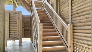 A wooden staircase with a metal railing leading to an upper level. - The Salty Mermaid 3 Bedroom Home (Port Bolivar)