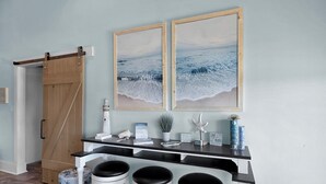 En bardisk med en träinredning, tre barstolar och två inramade tavlor med strandmotiv.
