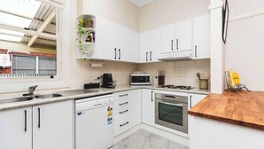 Een moderne keuken met witte kastjes, een vaatwasser, een magnetron, een oven en een houten aanrecht.