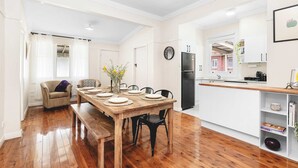 Een eethoek met een houten tafel voor vier personen, een bank en een keuken op de achtergrond.