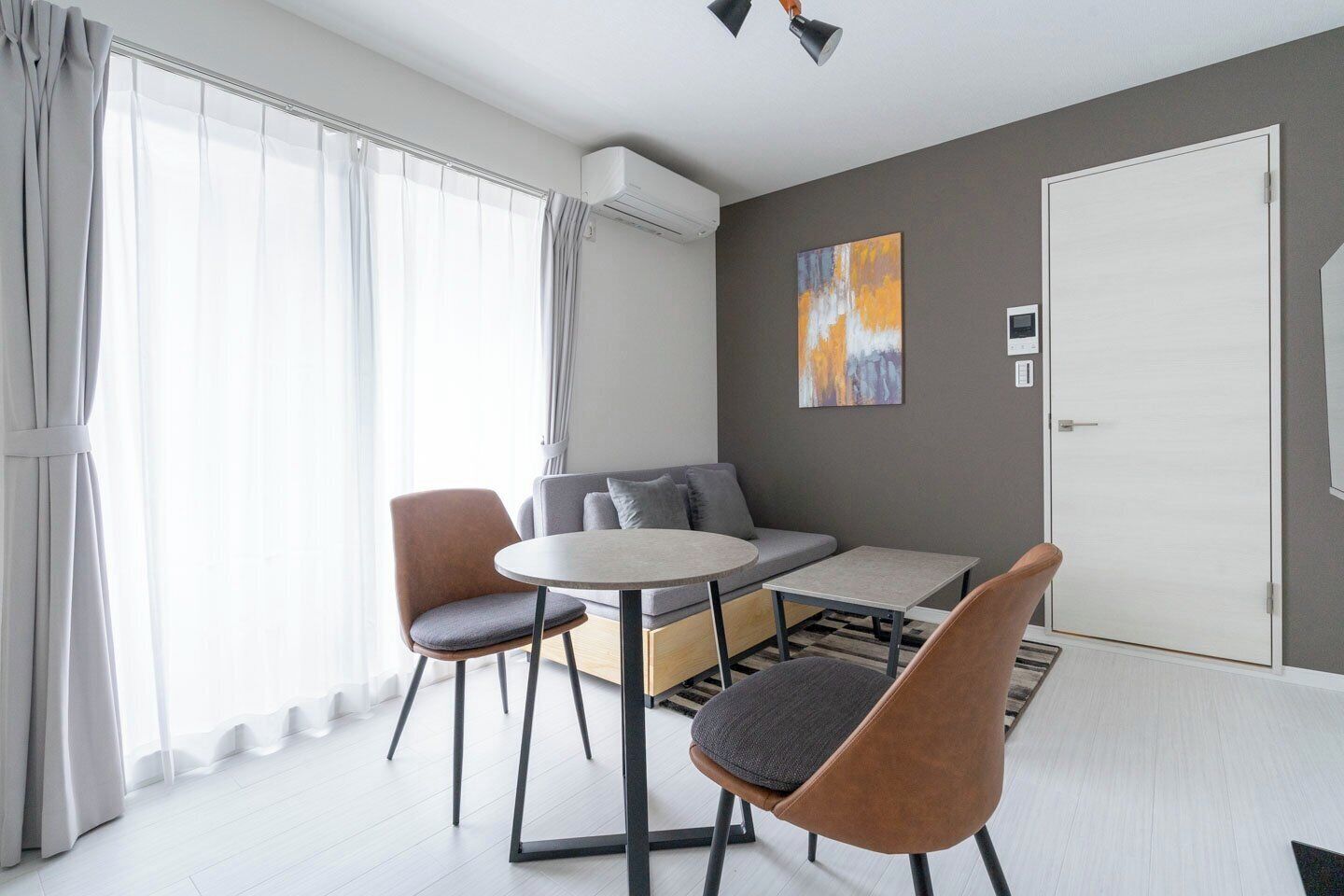 Un salon moderne avec un canapé, deux fauteuils, une petite table et un tableau accroché au mur.