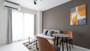 Een moderne woonkamer met een bank, twee fauteuils, een bijzettafeltje en een schilderij aan de muur.