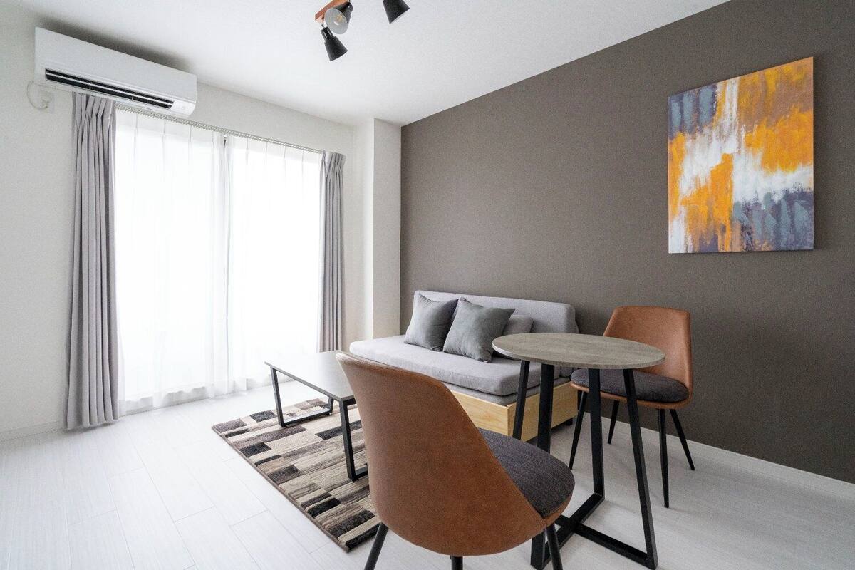 Un salon moderne avec un canapé, deux fauteuils, une petite table et un tableau accroché au mur.