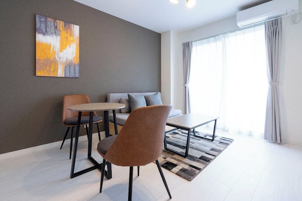 Una sala de estar moderna con un sofá, dos sillones, una mesa de centro y un cuadro en la pared.
