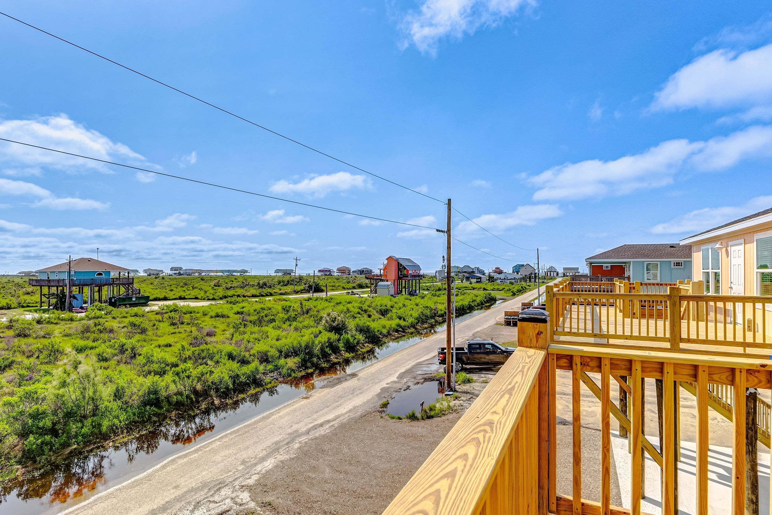 A coastal road with houses, a wooden bridge, and a small water body.