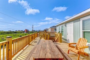 Terraza de madera con mesa y sillas, con vistas a un paisaje verde.
