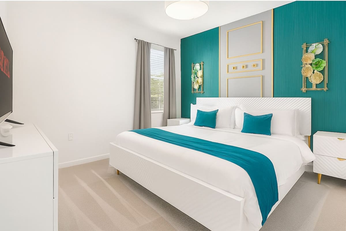 A modern hotel room with a large bed, a TV, and a desk.
