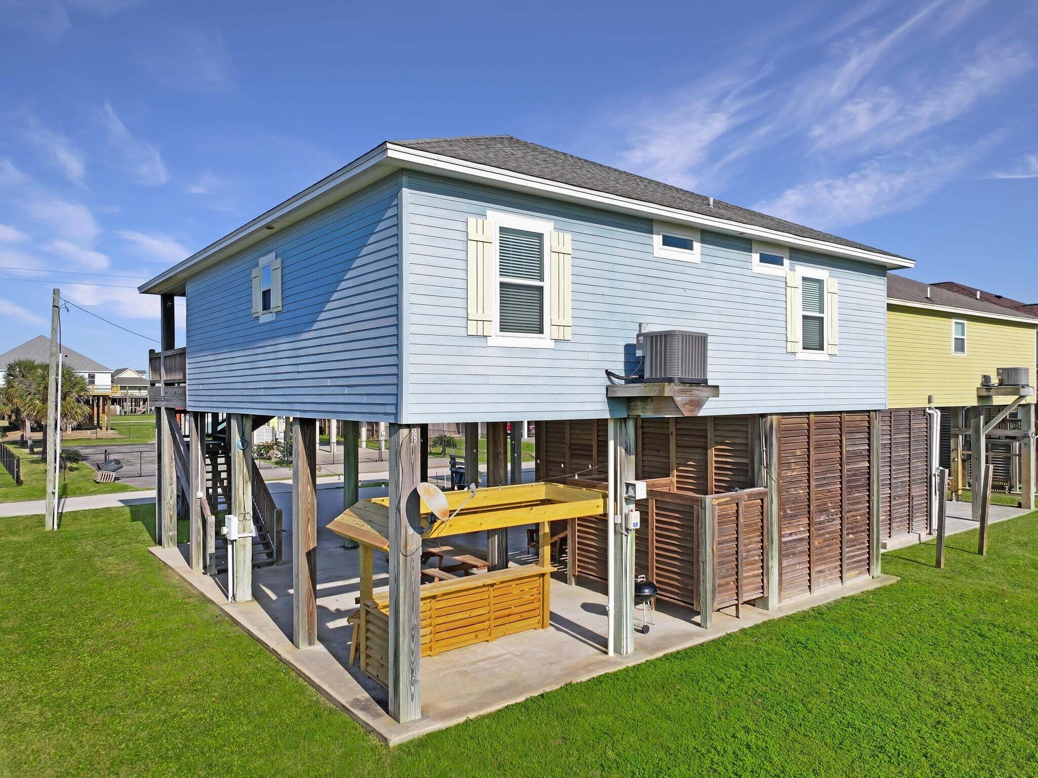 Ein zweistöckiges Haus mit überdachter Terrasse, Grill und Holzdeck.