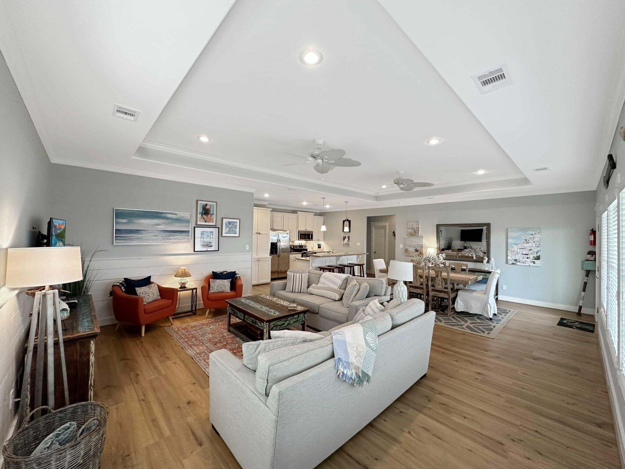 A spacious living room with a sofa, armchairs, a coffee table, and a dining area with chairs and a table.