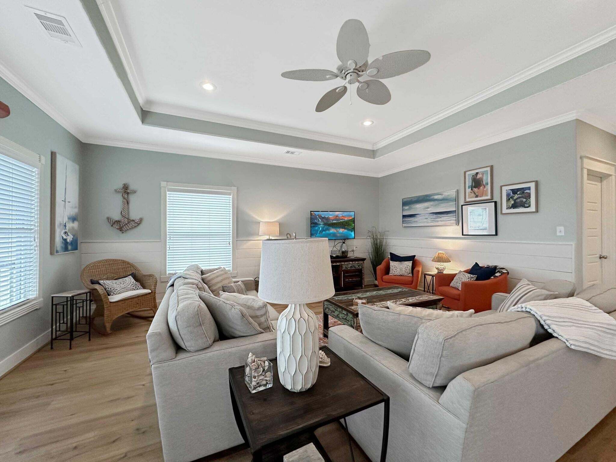 A living room with a ceiling fan, a TV, and a fireplace.
