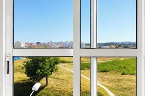 Ein Fenster mit Blick auf eine Stadtlandschaft und ein grünes Feld.