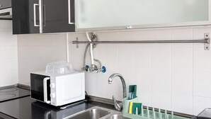 Ett modernt kök med inbyggd mikrovågsugn, diskho i rostfritt stål och en handduksställning.