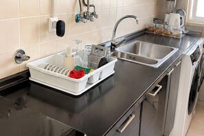 A kitchen with a stainless steel sink, a dish rack, a coffee maker, and a kettle. - Spacious Lisbon Apartment with 4 Bedrooms (Lisboa)