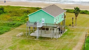 A single-story house with a balcony, located near a beach with waves in the background. - Bolivar Bliss 3 Bedroom Home (Port Bolivar)