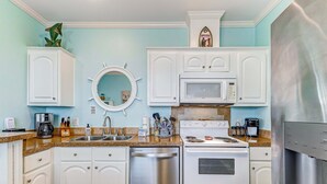 A kitchen with white cabinets, a dishwasher, a microwave, a stove, and a water dispenser. - Bolivar Bliss 3 Bedroom Home (Port Bolivar)